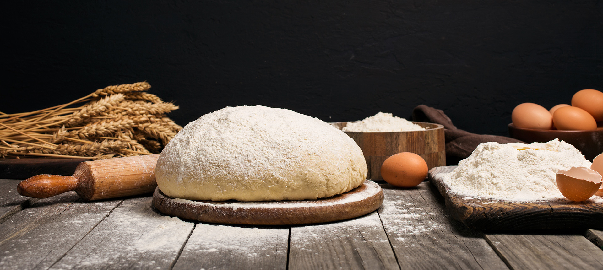A fresh Mama LaRosa dough ball dusted with flour on a wooden bench